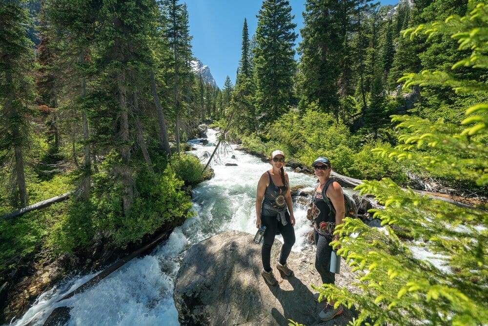 Two hikers at Hidden Falls on the Cascade Canyon Trail in Grand Teton National Park, Wyoming.