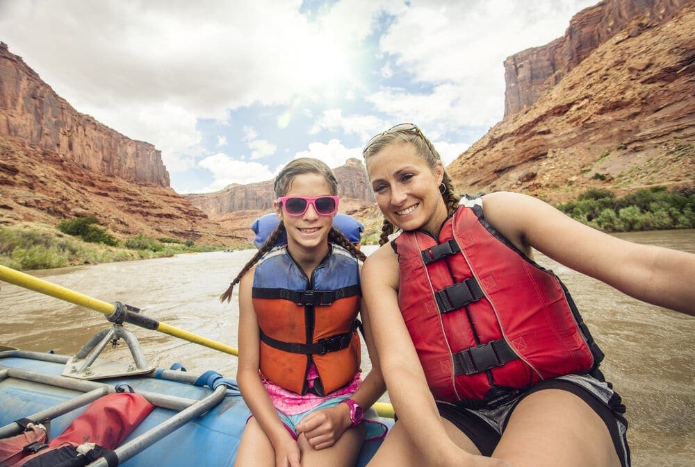 Active young family enjoying a day rafting down the Colorado River. A mother and her daughter sitting together on a large raft floating down the river near Moab, Utah.