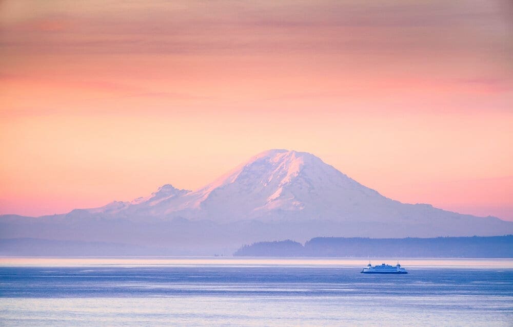 A ferry crossing the Puget Sound at sunrise with Mount Rainier in the background near Seattle, Washington