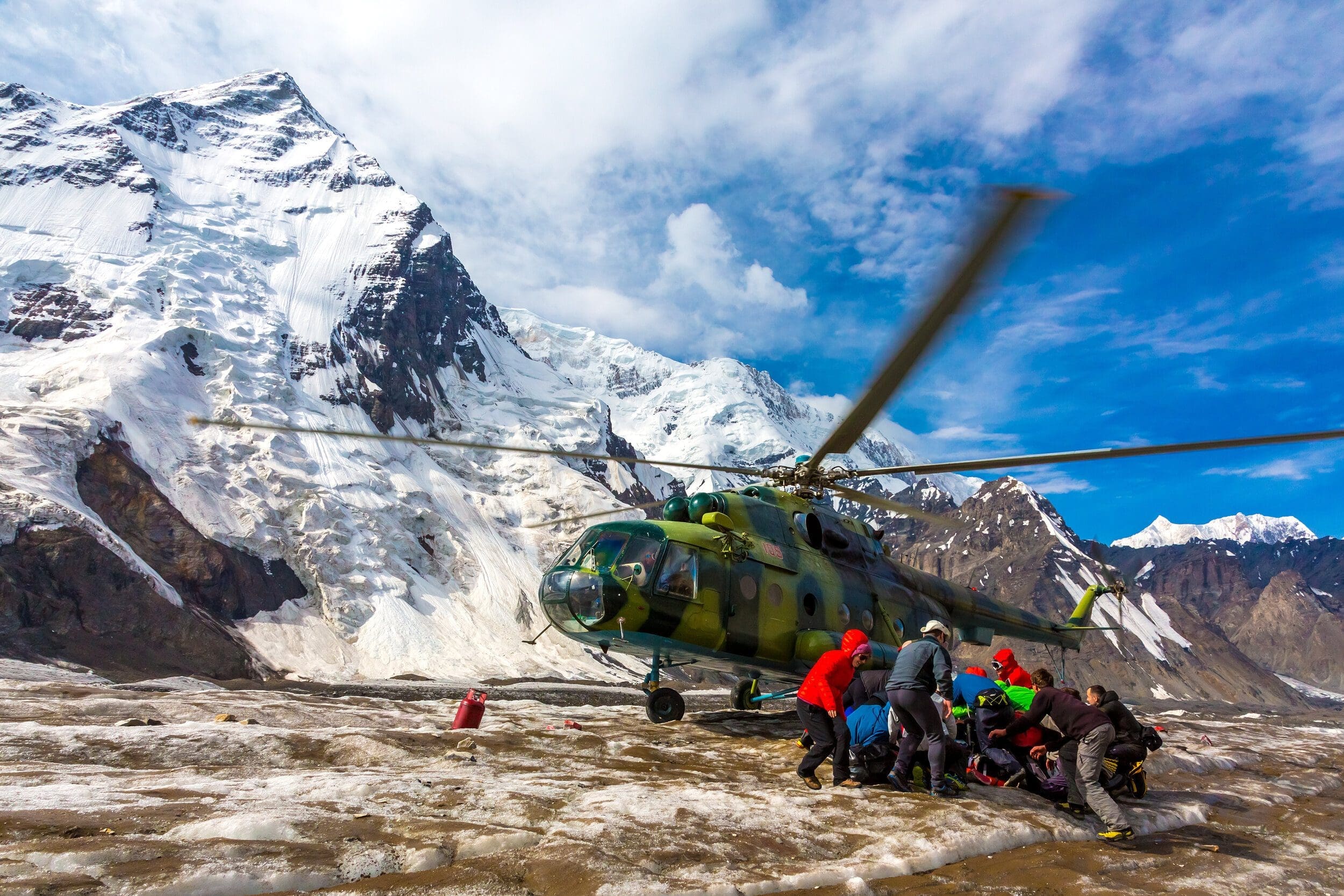 Helicopter Taking Off Ice Field of Massive Glacier and People Holding Luggage